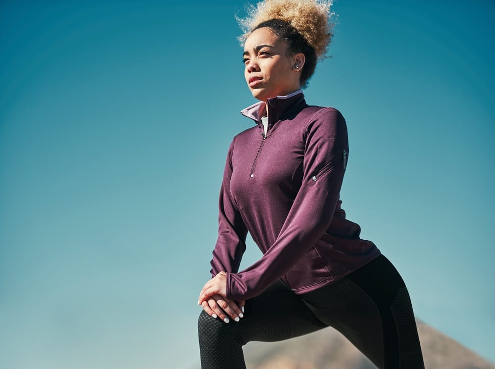 Cropped shot of a young woman stretching outdoors before her run.